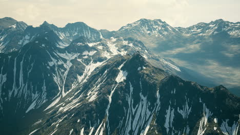 Aerial-Over-Valley-With-Snow-Capped-Mountains-In-Distance